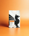 Coffee package with a black and white dog illustration on an orange gradient background