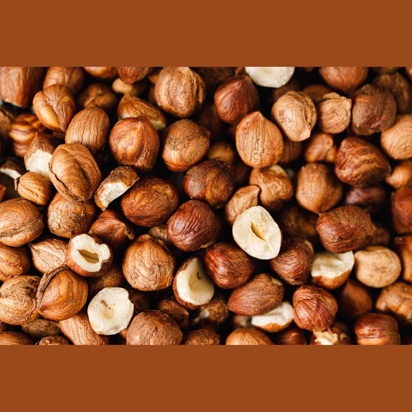 Macro close-up of whole and halved toasted hazelnuts showing creamy white meat and ridged brown shells