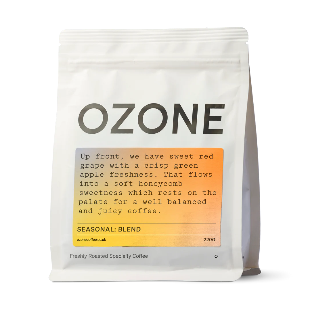 Ozone Seasonal Blend coffee beans in white matte resealable pouch with orange label showing red grape and green apple tasting notes