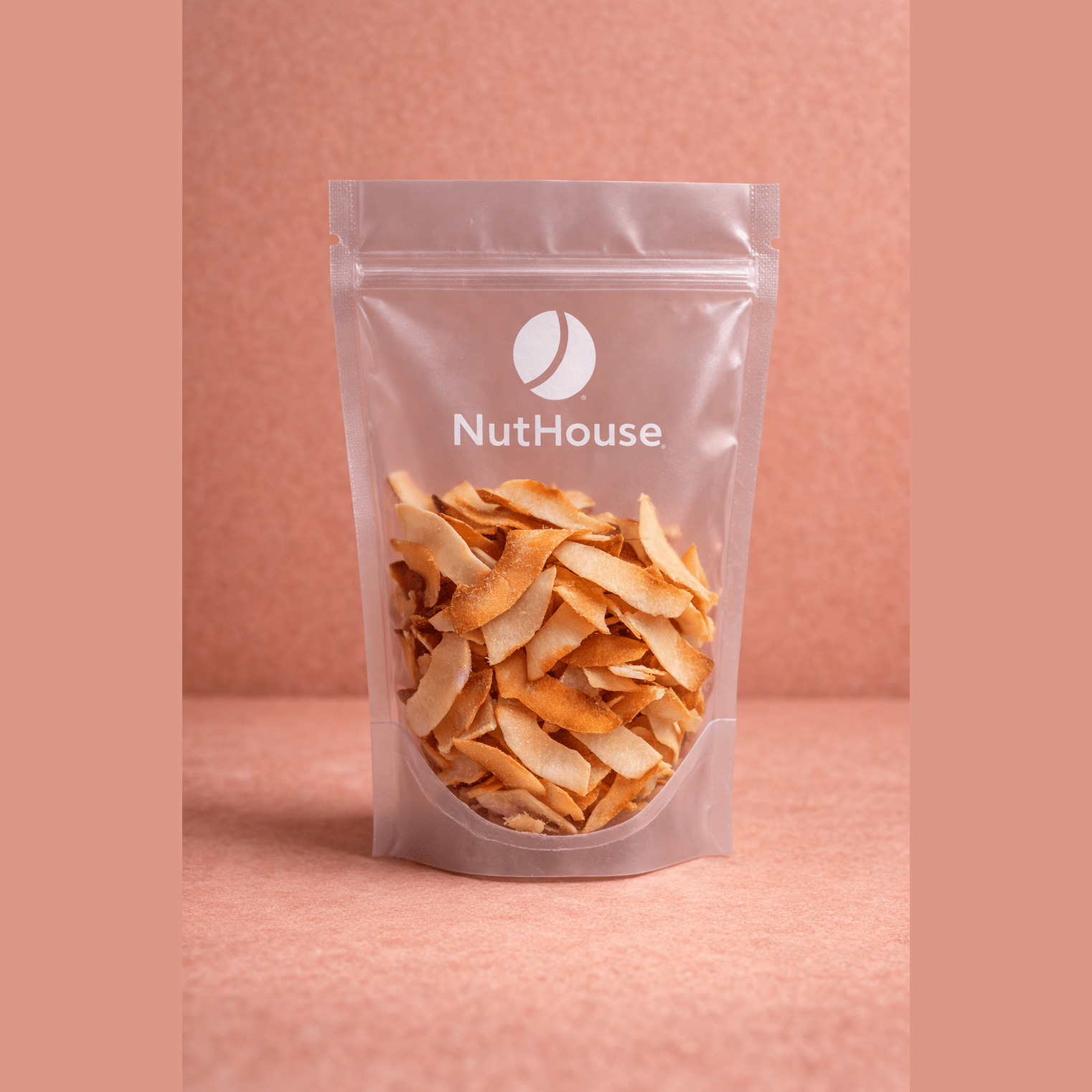 Nut House toasted coconut chips in clear resealable pouch showing wide golden-brown flakes with caramelized edges